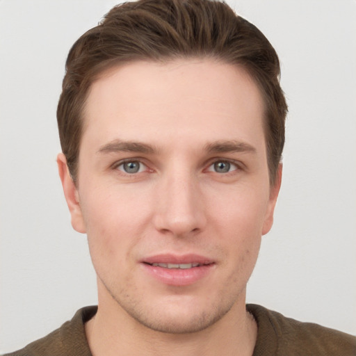 Joyful white young-adult male with short  brown hair and grey eyes