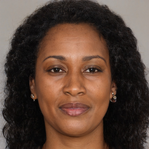 Joyful black adult female with long  brown hair and brown eyes