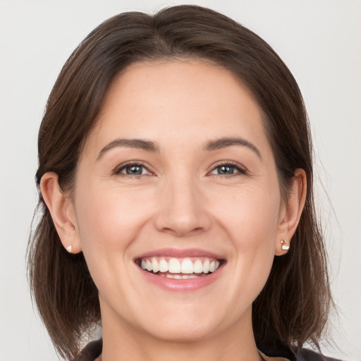 Joyful white young-adult female with medium  brown hair and grey eyes