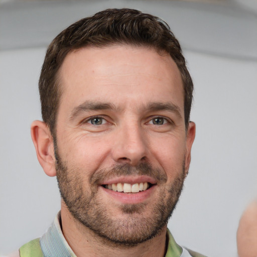 Joyful white young-adult male with short  brown hair and grey eyes