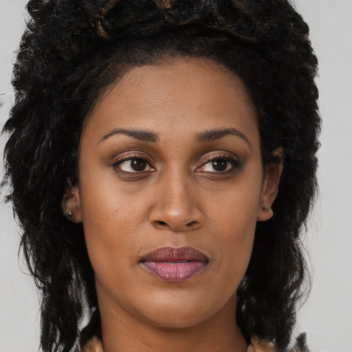 Joyful black young-adult female with long  brown hair and brown eyes