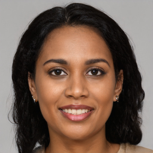 Joyful black young-adult female with long  black hair and brown eyes