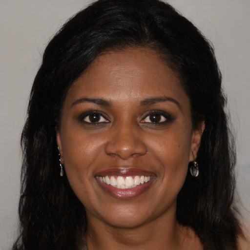 Joyful black young-adult female with long  black hair and brown eyes