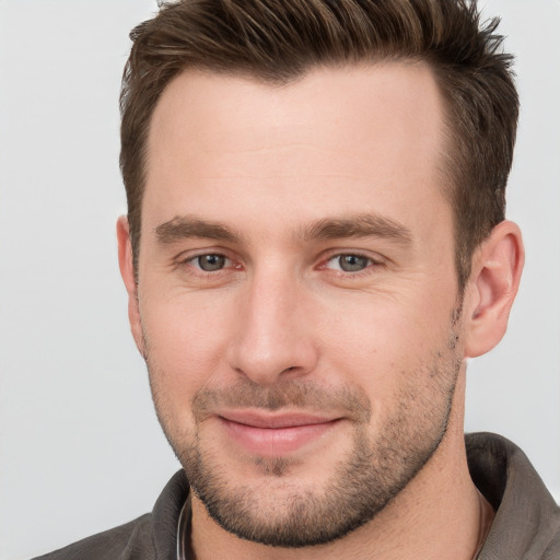 Joyful white young-adult male with short  brown hair and grey eyes