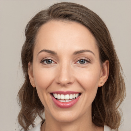 Joyful white young-adult female with medium  brown hair and grey eyes