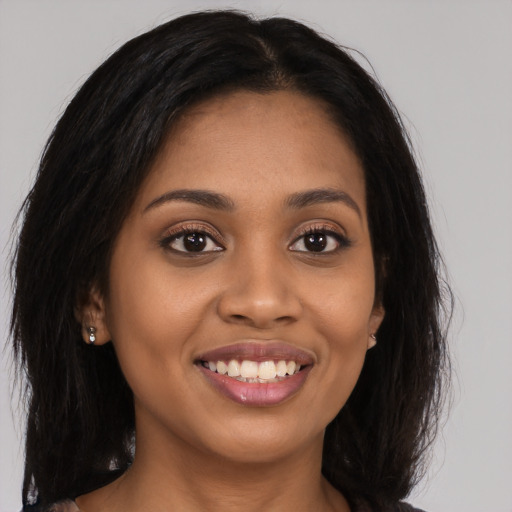 Joyful black young-adult female with long  brown hair and brown eyes