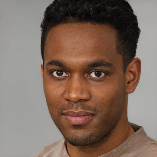Joyful black young-adult male with short  black hair and brown eyes