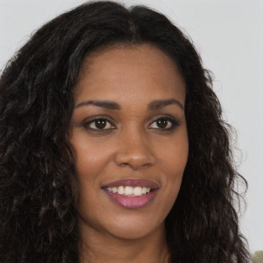 Joyful black young-adult female with long  brown hair and brown eyes