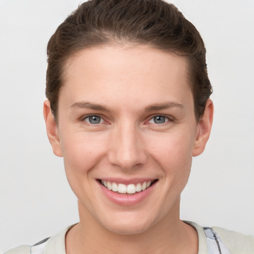 Joyful white young-adult female with short  brown hair and grey eyes