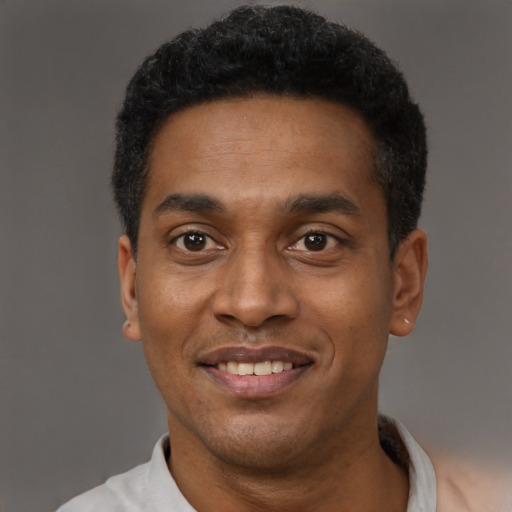 Joyful black young-adult male with short  black hair and brown eyes