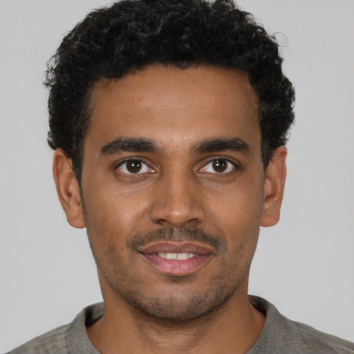Joyful black young-adult male with short  black hair and brown eyes