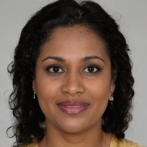 Joyful black young-adult female with long  brown hair and brown eyes