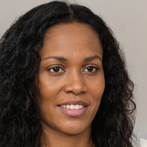 Joyful black young-adult female with long  brown hair and brown eyes