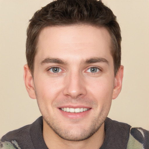 Joyful white young-adult male with short  brown hair and grey eyes