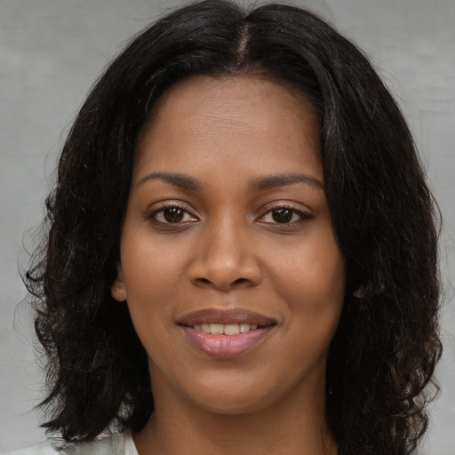 Joyful black young-adult female with long  black hair and brown eyes