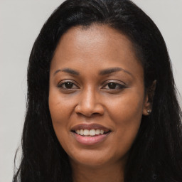 Joyful black young-adult female with long  brown hair and brown eyes