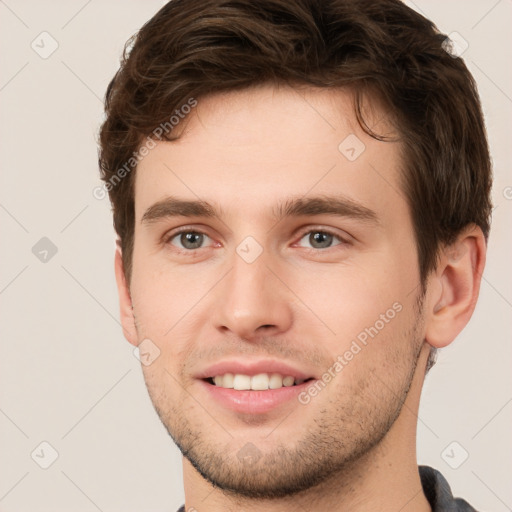 Joyful white young-adult male with short  brown hair and grey eyes