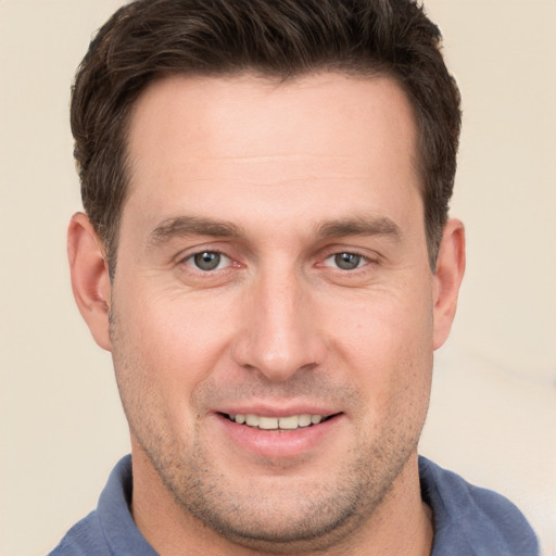 Joyful white young-adult male with short  brown hair and grey eyes