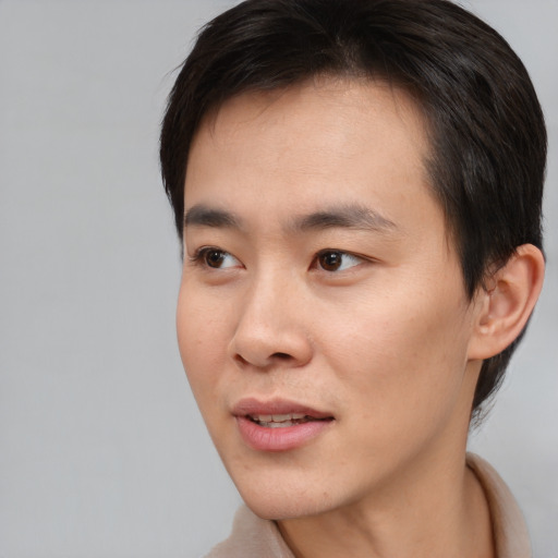 Joyful asian young-adult male with short  brown hair and brown eyes