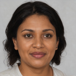 Joyful black adult female with medium  brown hair and brown eyes