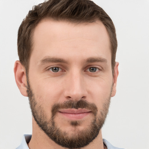 Joyful white young-adult male with short  brown hair and grey eyes