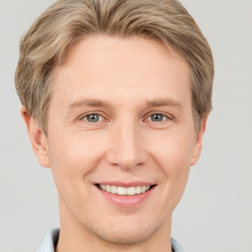 Joyful white young-adult male with short  brown hair and grey eyes