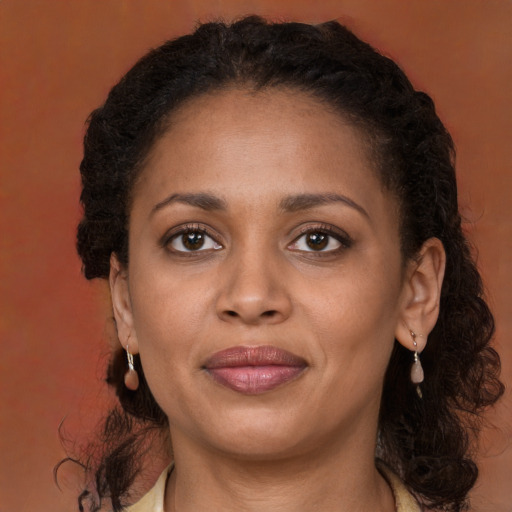 Joyful black adult female with long  brown hair and brown eyes