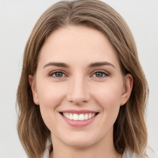 Joyful white young-adult female with medium  brown hair and grey eyes