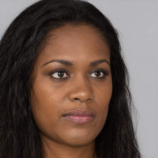 Joyful black young-adult female with long  brown hair and brown eyes