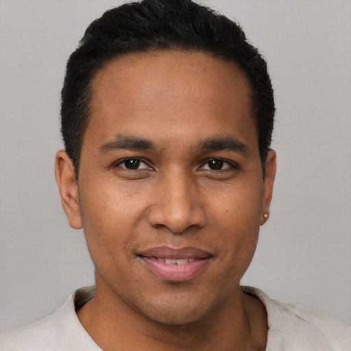 Joyful latino young-adult male with short  black hair and brown eyes
