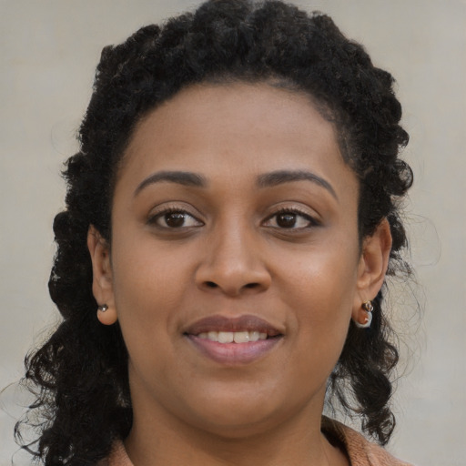 Joyful black young-adult female with long  brown hair and brown eyes