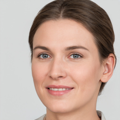 Joyful white young-adult female with medium  brown hair and grey eyes