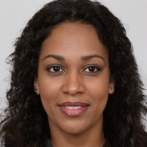 Joyful black young-adult female with long  brown hair and brown eyes