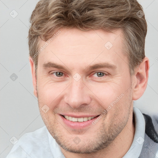 Joyful white young-adult male with short  brown hair and grey eyes