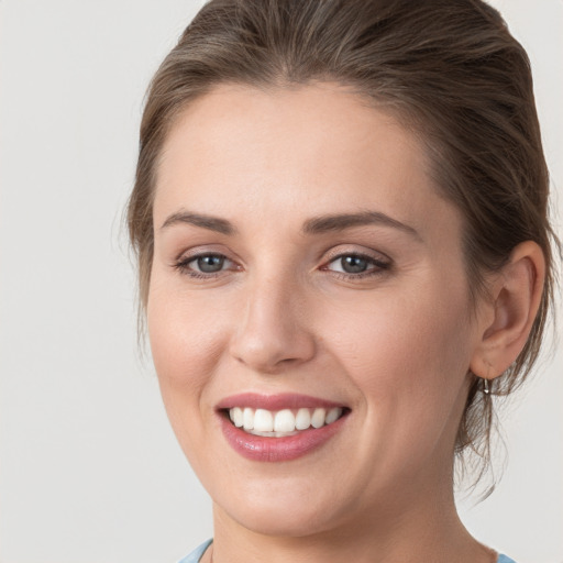 Joyful white young-adult female with medium  brown hair and grey eyes