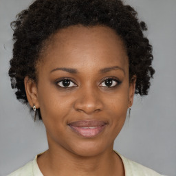 Joyful black young-adult female with short  brown hair and brown eyes