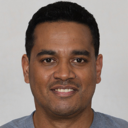 Joyful black young-adult male with short  black hair and brown eyes