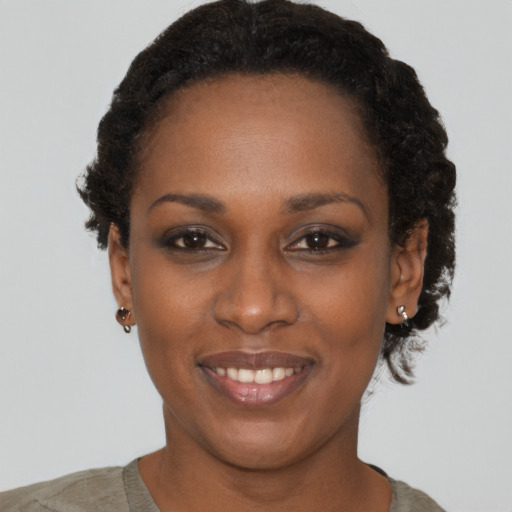 Joyful black young-adult female with short  black hair and brown eyes