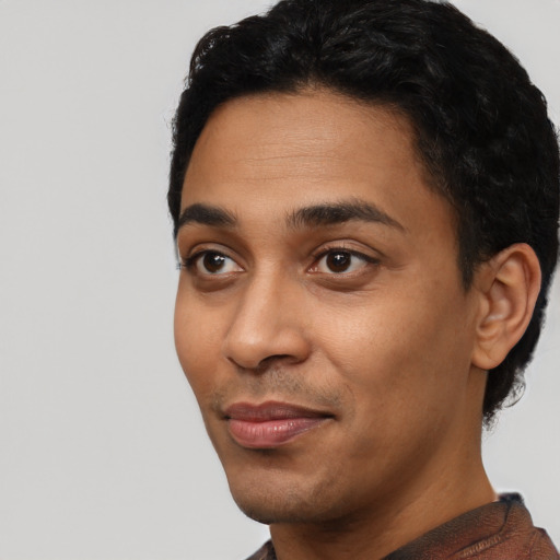 Joyful latino young-adult male with short  black hair and brown eyes