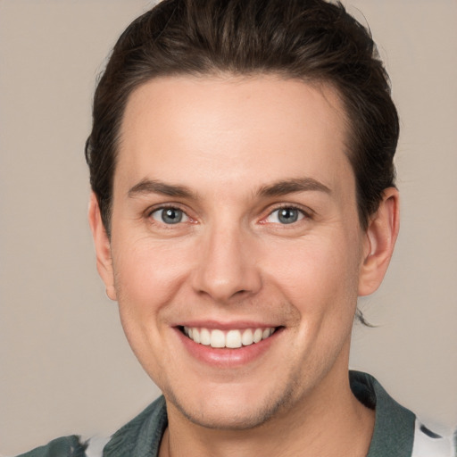 Joyful white young-adult male with short  brown hair and grey eyes