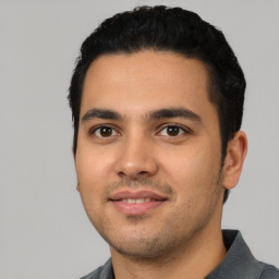 Joyful latino young-adult male with short  black hair and brown eyes