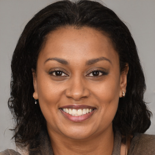 Joyful black adult female with medium  brown hair and brown eyes