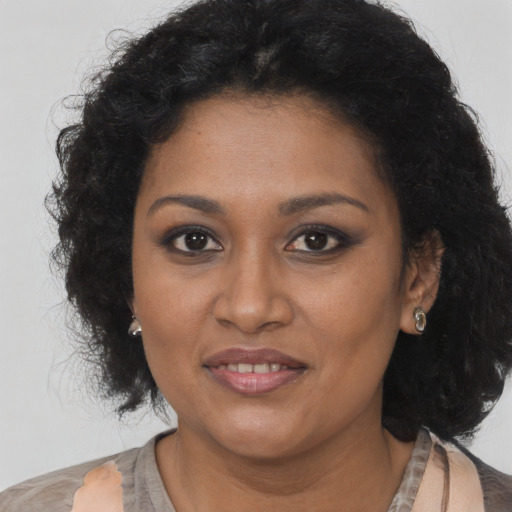 Joyful black young-adult female with long  brown hair and brown eyes