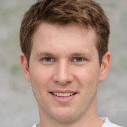 Joyful white young-adult male with short  brown hair and grey eyes