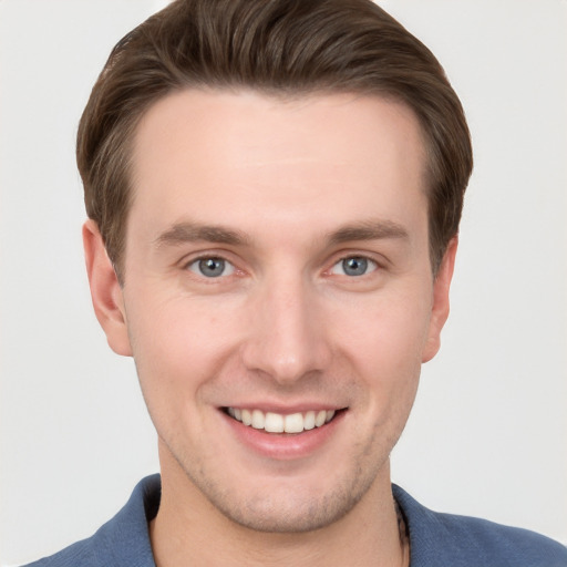 Joyful white young-adult male with short  brown hair and grey eyes