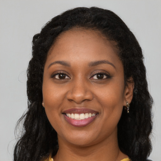 Joyful black young-adult female with long  brown hair and brown eyes