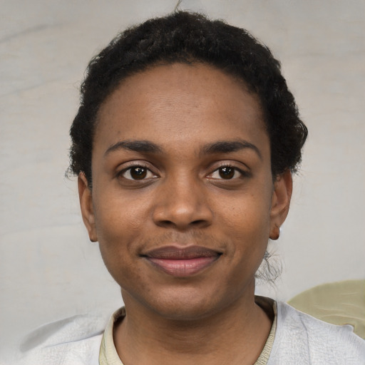 Joyful black young-adult female with short  black hair and brown eyes