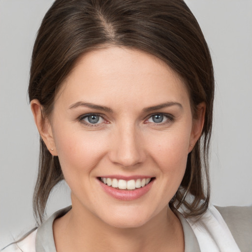 Joyful white young-adult female with medium  brown hair and grey eyes