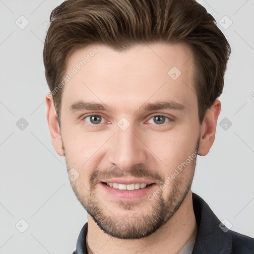 Joyful white young-adult male with short  brown hair and grey eyes