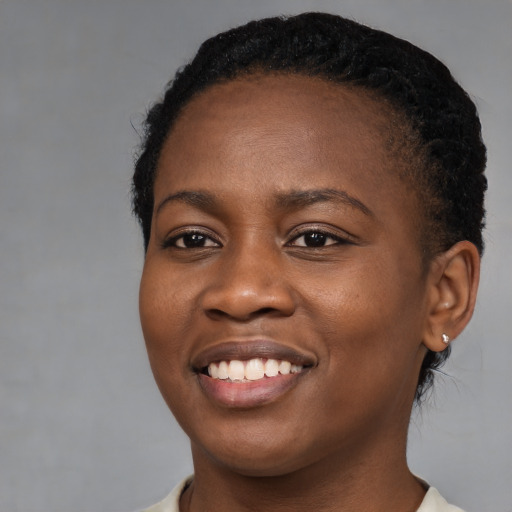 Joyful black young-adult female with short  black hair and brown eyes